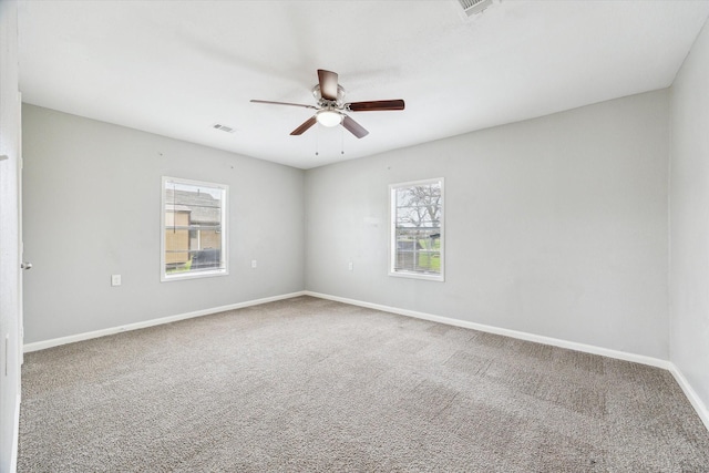 carpeted spare room featuring a ceiling fan, visible vents, and baseboards