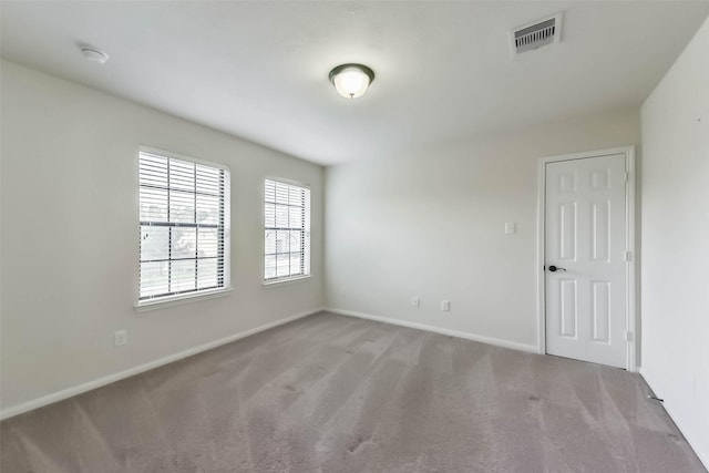 empty room with visible vents, light carpet, and baseboards