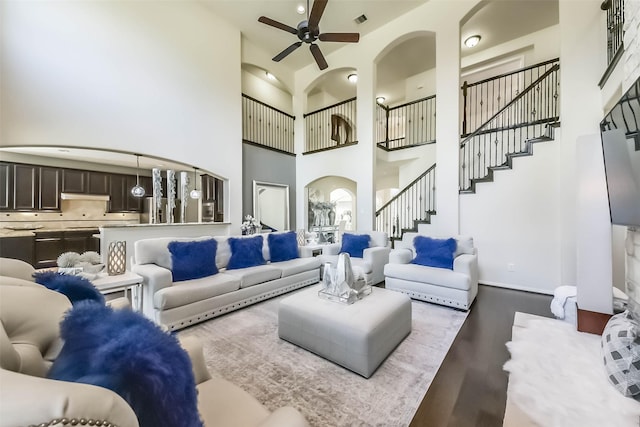 living area featuring visible vents, a high ceiling, ceiling fan, wood finished floors, and stairs