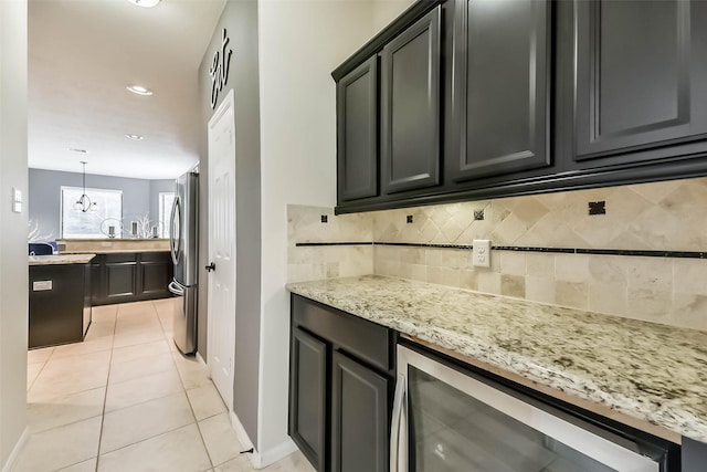 kitchen featuring light tile patterned floors, beverage cooler, freestanding refrigerator, light stone countertops, and backsplash