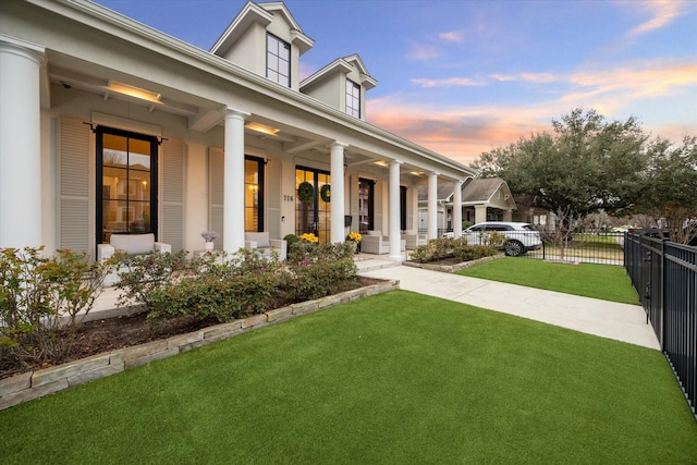 view of front facade featuring a porch, fence, and a front lawn