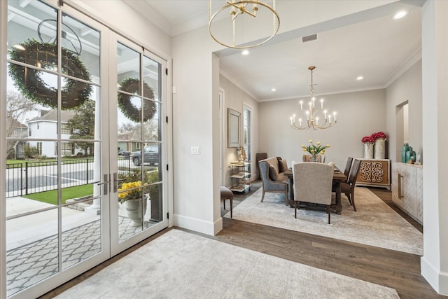 dining space with a healthy amount of sunlight, wood finished floors, visible vents, and an inviting chandelier