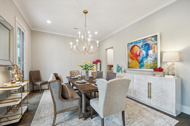 dining room featuring visible vents, crown molding, an inviting chandelier, and wood finished floors