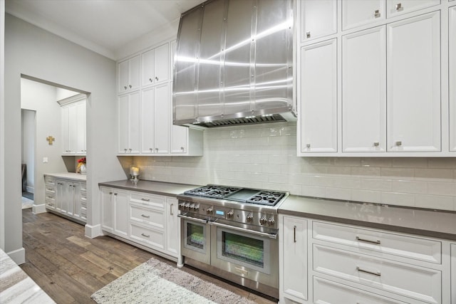 kitchen featuring white cabinets, dark wood finished floors, range hood, double oven range, and backsplash