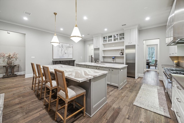 kitchen featuring white cabinets, high end appliances, an island with sink, dark wood-style floors, and recessed lighting