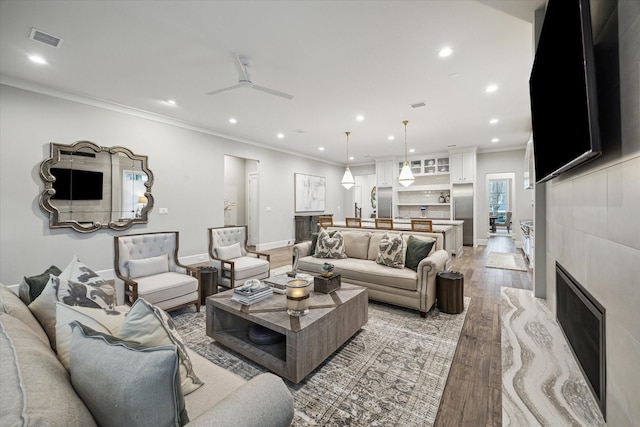 living area featuring crown molding, recessed lighting, visible vents, light wood-style floors, and baseboards