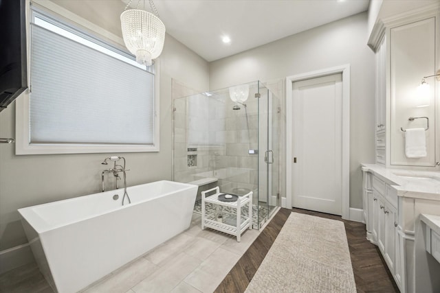 full bath featuring a soaking tub, wood finished floors, vanity, a shower stall, and recessed lighting