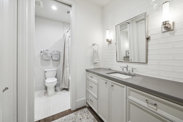 full bath with toilet, vanity, baseboards, visible vents, and decorative backsplash