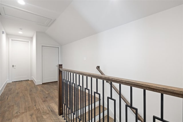 corridor featuring baseboards, vaulted ceiling, hardwood / wood-style floors, and an upstairs landing