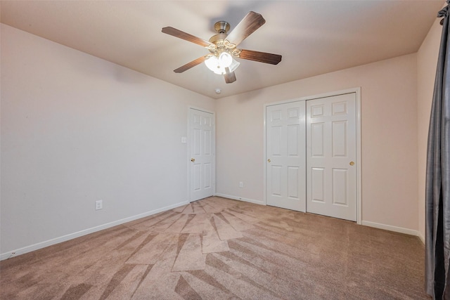 unfurnished bedroom featuring light carpet, ceiling fan, a closet, and baseboards