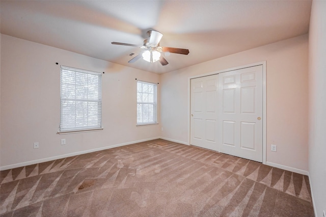 unfurnished bedroom featuring a ceiling fan, visible vents, carpet, baseboards, and a closet