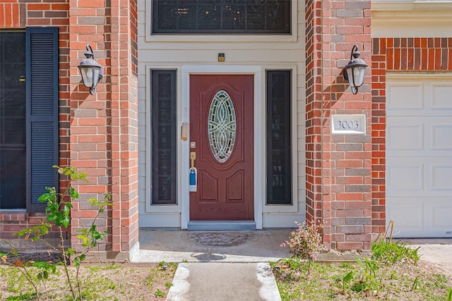 entrance to property with brick siding and a garage