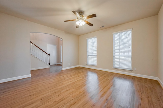 3003 Sage Grouse Ct, Rosenberg, TX 77471 - spare room with arched walkways, light wood finished floors, ceiling fan, baseboards, and stairway