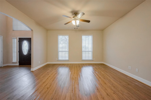 foyer entrance with ceiling fan, baseboards, arched walkways, and light wood-style flooring