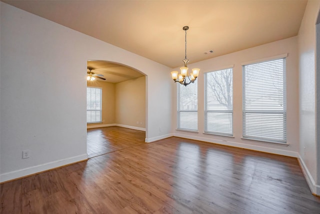 unfurnished room featuring arched walkways, visible vents, a healthy amount of sunlight, and wood finished floors