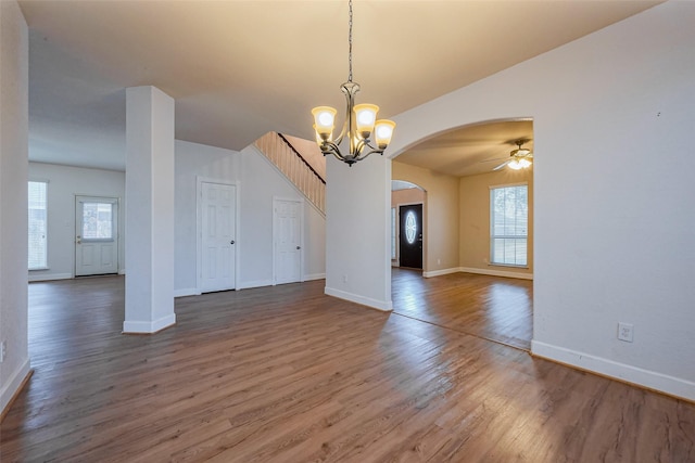 interior space with ceiling fan with notable chandelier, wood finished floors, arched walkways, and baseboards