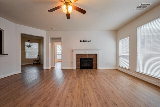 unfurnished living room featuring visible vents, baseboards, light wood-style flooring, a tile fireplace, and a ceiling fan