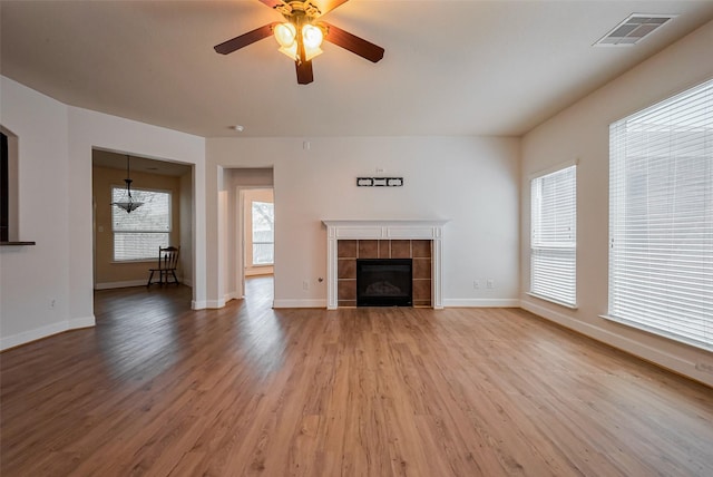 3003 Sage Grouse Ct, Rosenberg, TX 77471 - unfurnished living room featuring light wood-type flooring, ceiling fan, a tiled fireplace, and baseboards