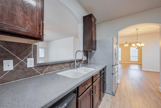 kitchen with light wood-type flooring, a sink, arched walkways, decorative backsplash, and dark brown cabinets