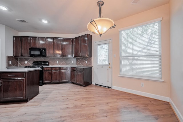 kitchen featuring visible vents, stainless steel range with gas stovetop, light wood-style floors, black microwave, and backsplash