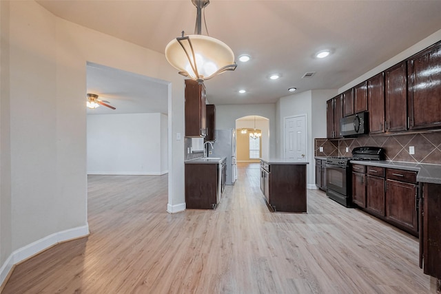 kitchen with visible vents, arched walkways, black appliances, dark brown cabinets, and tasteful backsplash