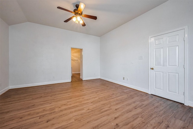 spare room with a ceiling fan, vaulted ceiling, wood finished floors, and baseboards