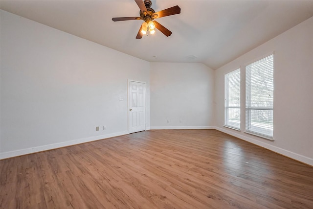 empty room featuring ceiling fan, baseboards, wood finished floors, and vaulted ceiling