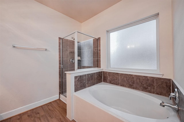 bathroom with baseboards, wood finished floors, a garden tub, and a stall shower