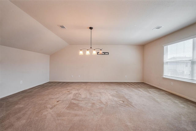 carpeted empty room featuring visible vents, baseboards, and lofted ceiling