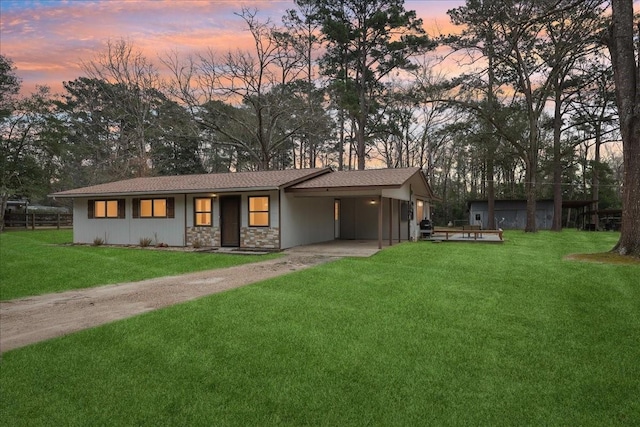 view of front of property featuring driveway, stone siding, a carport, and a front yard