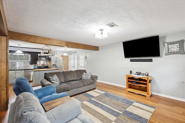 living area featuring light wood-type flooring, visible vents, and baseboards