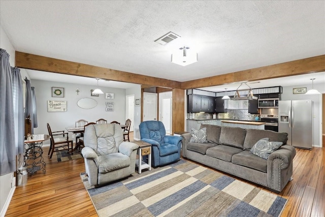 living area featuring dark wood-style flooring, beamed ceiling, and visible vents