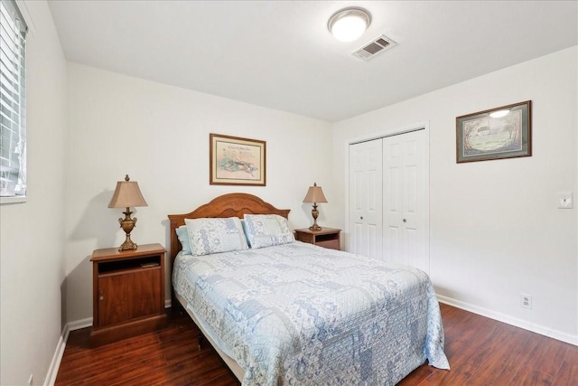 bedroom with baseboards, a closet, visible vents, and dark wood-type flooring