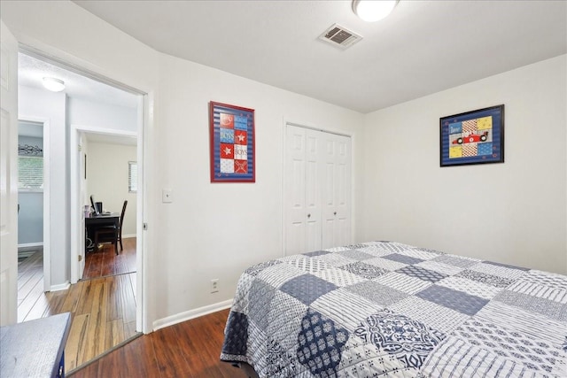 bedroom with baseboards, a closet, visible vents, and dark wood-type flooring