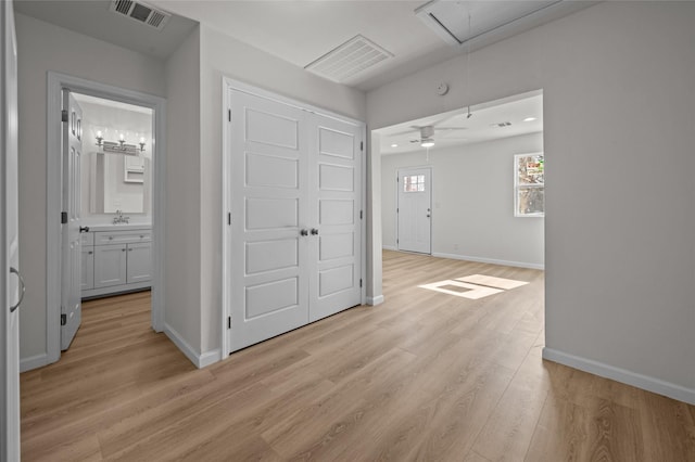 interior space with attic access, visible vents, baseboards, light wood-style flooring, and a sink