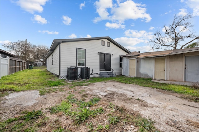 rear view of property featuring entry steps, central air condition unit, and fence