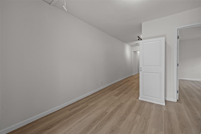 spare room with light wood-type flooring, attic access, and baseboards