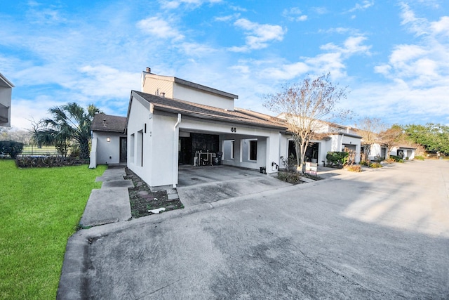 back of house featuring concrete driveway, a lawn, an attached garage, and stucco siding