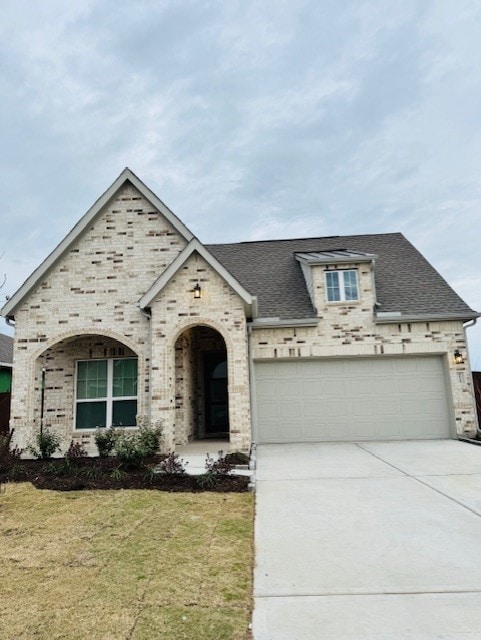 view of front of property featuring a garage, a front yard, driveway, and a shingled roof