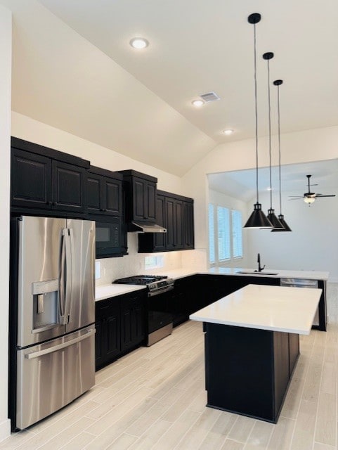 kitchen featuring decorative light fixtures, light countertops, appliances with stainless steel finishes, a kitchen island, and dark cabinetry