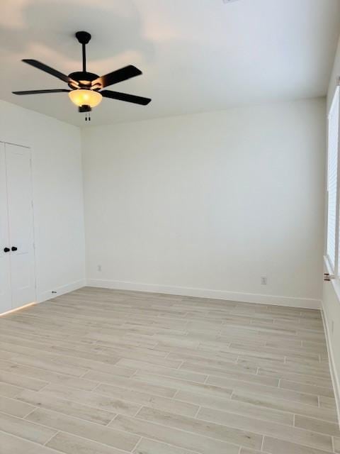 spare room with a ceiling fan, light wood-type flooring, and baseboards