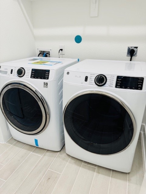 clothes washing area featuring washing machine and dryer, laundry area, and wood tiled floor