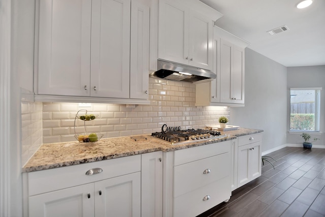 kitchen with stainless steel gas cooktop, visible vents, white cabinetry, light stone countertops, and under cabinet range hood