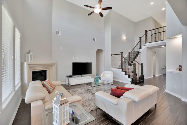 living area with arched walkways, stairway, dark wood-style flooring, and visible vents