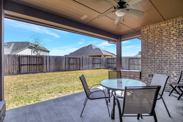 view of patio featuring outdoor dining space, a fenced backyard, and a ceiling fan