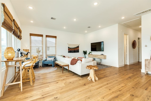 living area with light wood-type flooring, attic access, visible vents, and recessed lighting