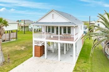 back of house with a carport, a porch, a lawn, and driveway