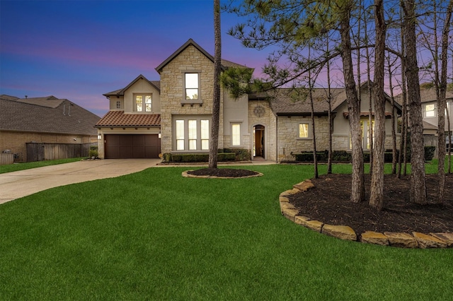 view of front of house featuring concrete driveway, an attached garage, a front yard, fence, and stone siding