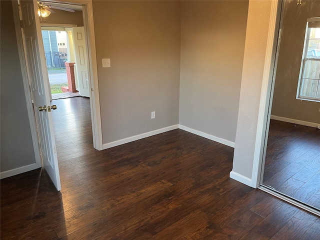 spare room featuring ceiling fan, baseboards, and dark wood-type flooring