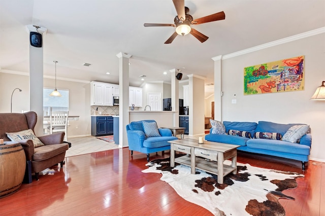 living area with visible vents, a ceiling fan, light wood-style flooring, and crown molding